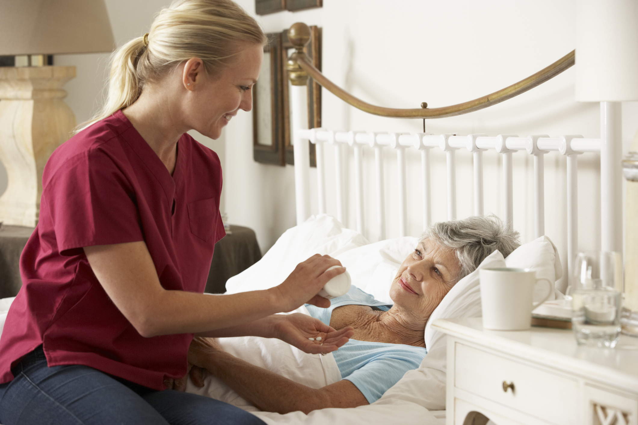 Health Visitor Giving Senior Woman Medication In Bed